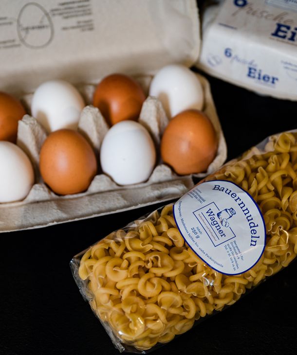 Frische Hühnereier in einer Schachtel und Eiernudeln in der Verpackung
