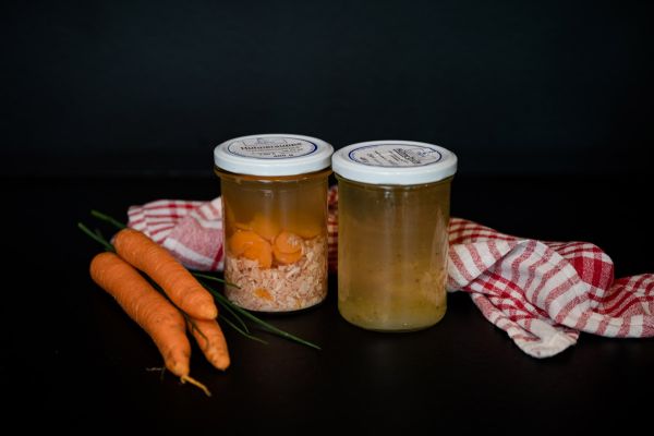 Zwei Einmachgläser mit Hühnerbrühe und Hühnersuppe